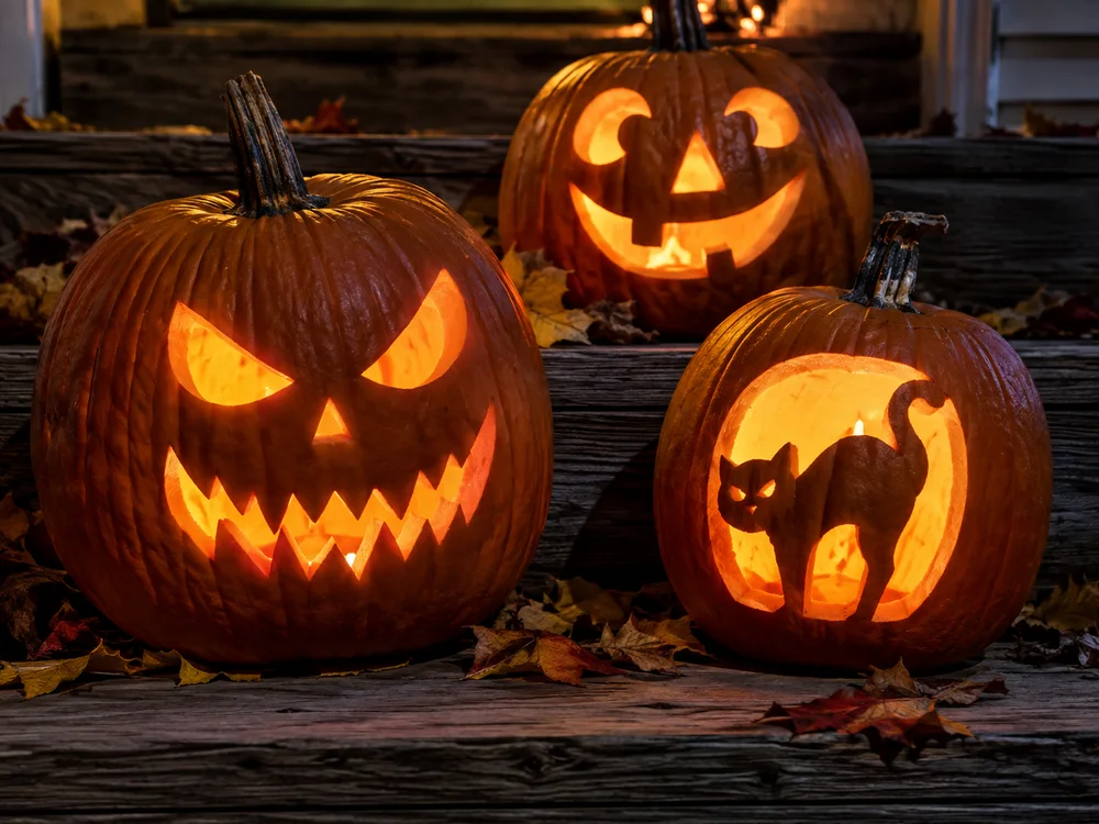Illustrative close-up of glowing jack-o-lanterns on porch steps